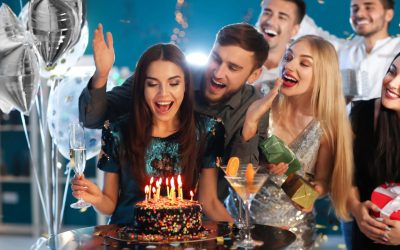 Young woman with friends near her birthday cake at party in club